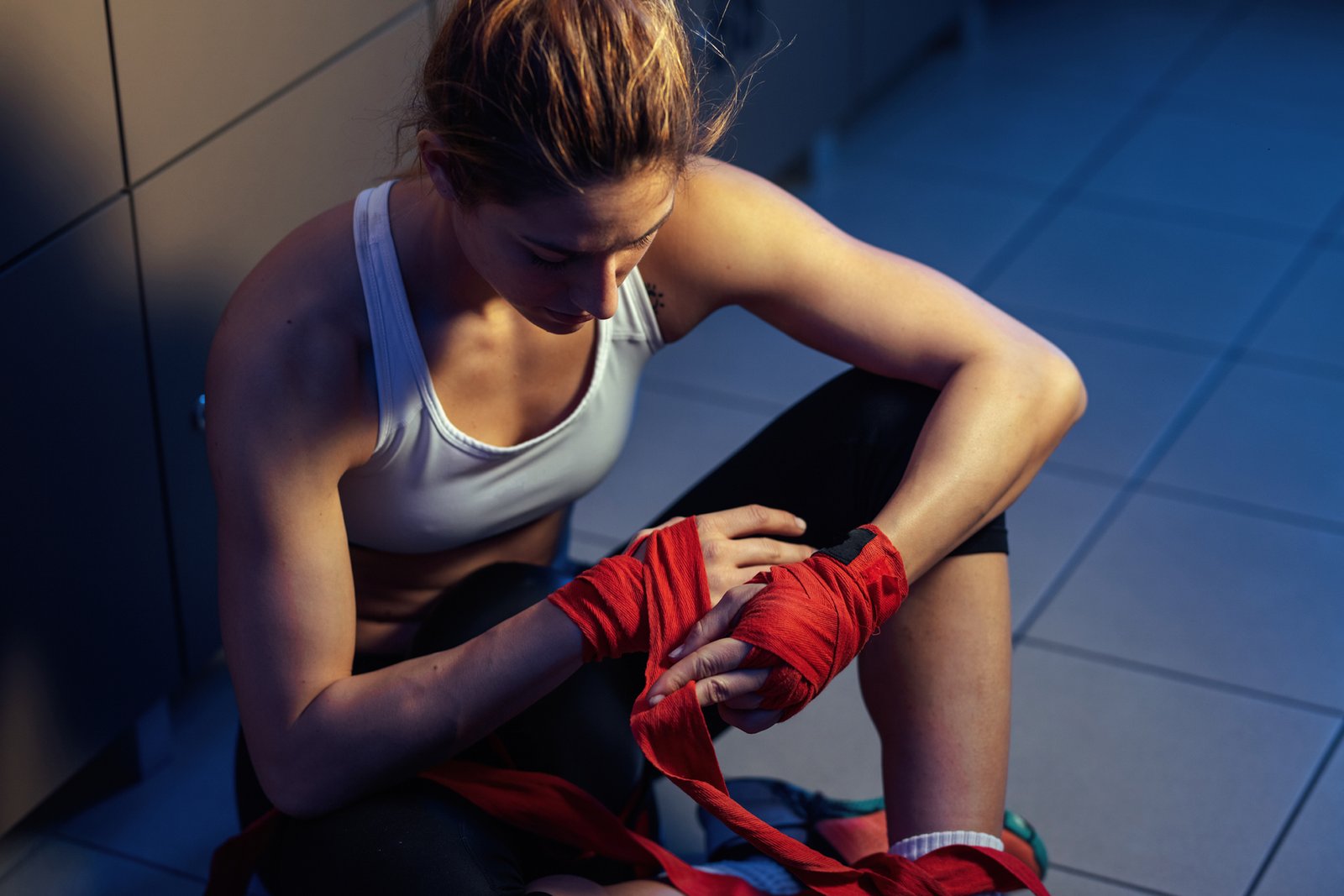 Above view of female athlete wrapping hands with boxing straps before sports training.